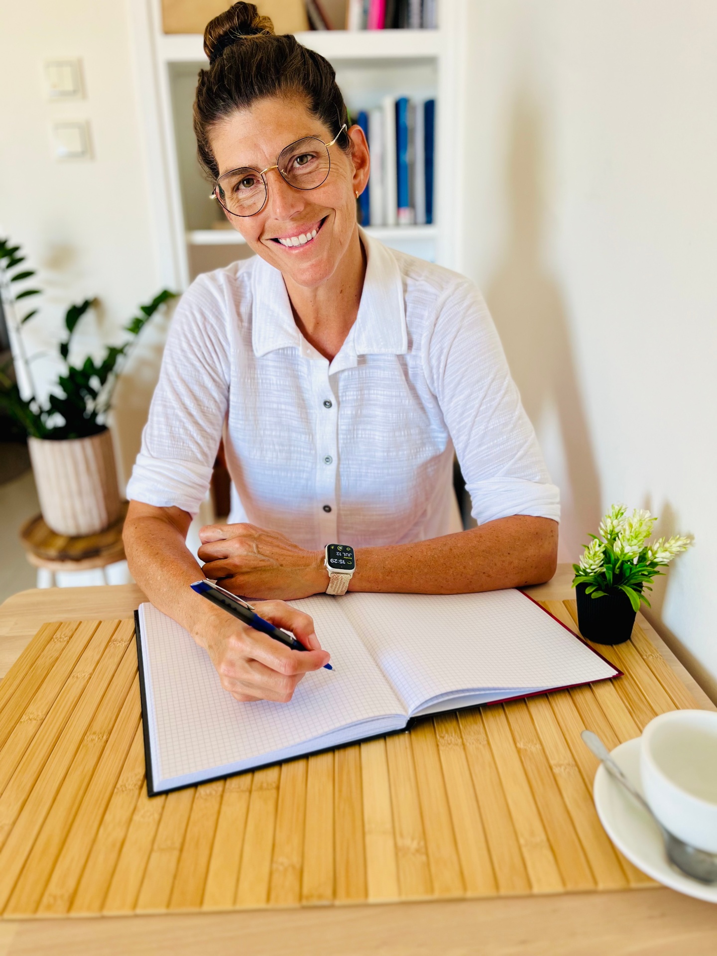 Anita, founder of Lightbulb Moment Health, writing in a notebook at her desk.