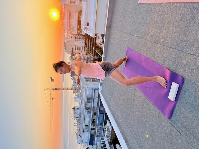 Anita practising yoga on a rooftop at sunset.